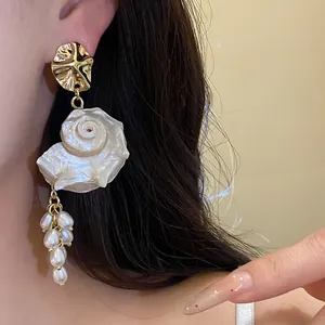 Macro view of vintage French shell and pearl tassel earrings worn on a model's ear