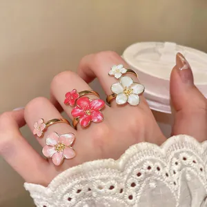 Dettaglio di tre eleganti anelli a fiore in smalto in stile coreano in rosa e bianco sulla mano