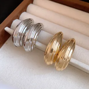 Primo piano dettagliato di orecchini a goccia oro e argento con righe metalliche.