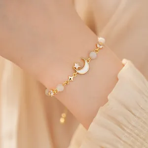 Detailed close-up of a gold cat-eye stone moon bracelet with sparkling zircon on a wrist.