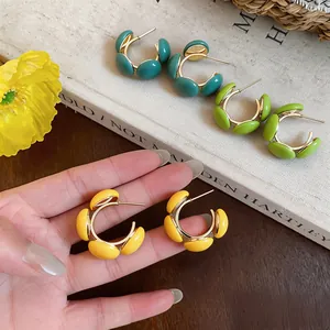Vue détaillée de boucles d'oreilles créoles C en résine jaune vif avec des touches dorées