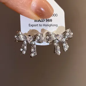 Macro detail of elegant bow stud earrings featuring sparkling zircons and delicate pearls