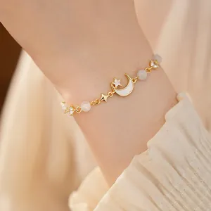 Close-up of a gold-plated moon and star bracelet with cat's eye stone on a wrist.