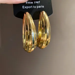 Dettaglio di eleganti orecchini a goccia color oro con raffinata texture a coste