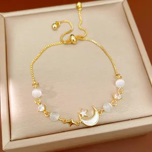 Detailed view of gold-plated moon and star charm bracelet with cat eye stone beads