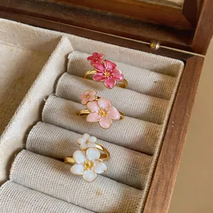 Dettaglio di tre eleganti anelli a fiore in tonalità rosa in un portagioie di legno
