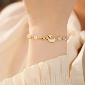 Detailed view of elegant gold moon and star bracelet with cat eye stones on a wrist