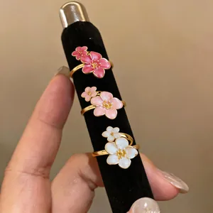 Primo piano di anelli a forma di fiore in smalto rosa e bianco su un supporto nero