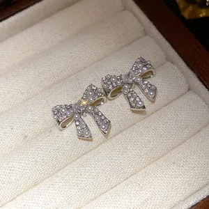Close-up view of elegant silver bow earrings with sparkling zircons and pearls
