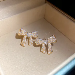 Macro view of 18k gold plated bow earrings featuring zircons and delicate pearls