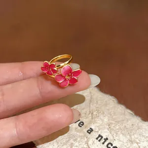 Primo piano di un anello in smalto dorato con due fiori di prugno rosa, regolabile