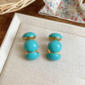 Vue détaillée de boucles d'oreilles en résine turquoise à trois perles et base dorée