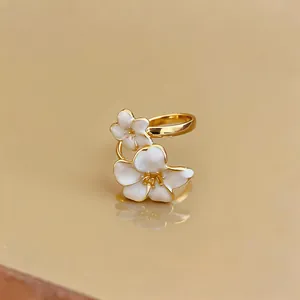 Dettaglio macro di un anello placcato oro con eleganti petali di fiori in smalto bianco