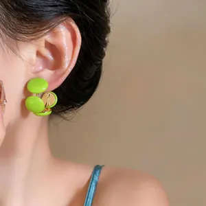 Vue détaillée de boucles d'oreilles en résine vert vif en forme de C portées par un mannequin