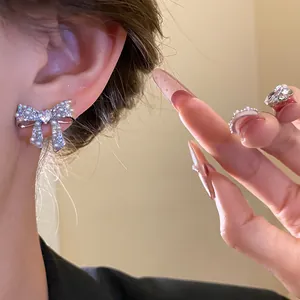 Close-up view of elegant 18k gold plated bow earrings with pearls and zircons on ear