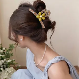Elegant large floral fabric hair claw clip with yellow resin flower worn by a model