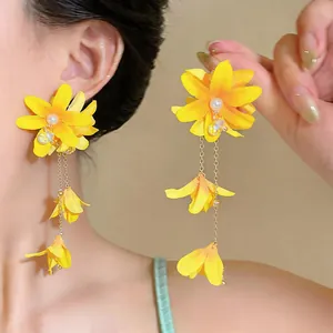 Close-up detail of yellow fabric flower tassel earrings with pearls and silver needles