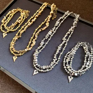 Dettaglio di set collana e bracciale retrò con perline e ciondoli a cuore oro e argento