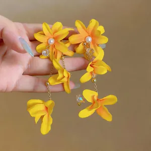 Close-up detail of yellow fabric flower tassel earrings with elegant white pearls