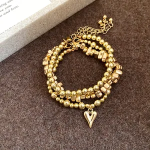Dettaglio del set collana e bracciale con perline dorate e ciondolo a cuore lucido