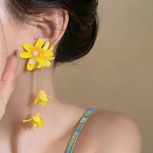 Macro detail view of elegant yellow fabric flower earrings with long pearl tassels