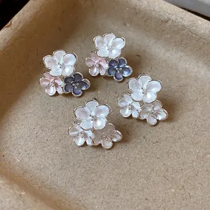 Close-up detail of elegant enamel flower stud earrings in white, pink and blue colors
