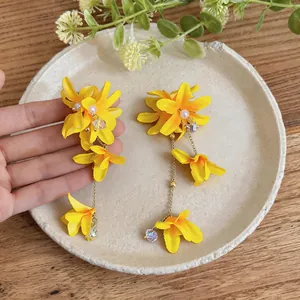 Close-up of elegant yellow fabric flower earrings featuring pearls and long tassels