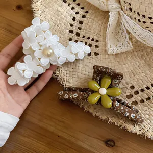 Detailed view of two Mori style floral fabric hair claw clips resting on a straw hat