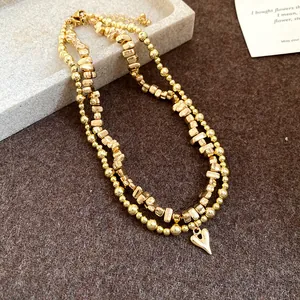 Dettaglio macro di una collana vintage dorata a doppio strato con ciondolo a cuore.