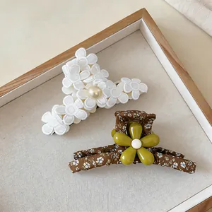 Detail view of large floral fabric hair claw clips in white and forest style