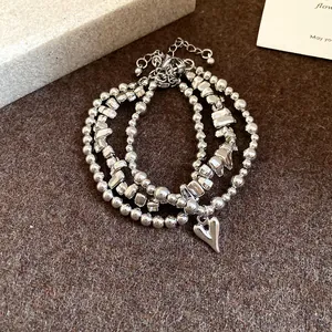 Dettaglio del set di bracciali con perline d'argento vintage e ciondolo a cuore