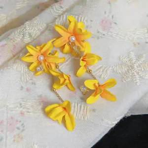 Close-up macro view of vibrant yellow fabric flower earrings with pearls and crystal drops.