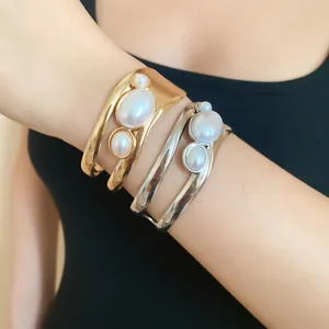 Close-up of vintage hollow cuff bracelets with three elegant pearls on model wrist