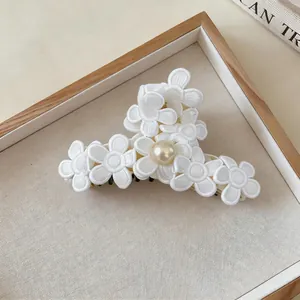 Detailed view of large fabric flower hair claw clip with embroidered petals and pearl center