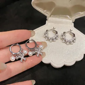 Eleganti orecchini a cerchio in argento con perle e zirconi in un portagioie a conchiglia