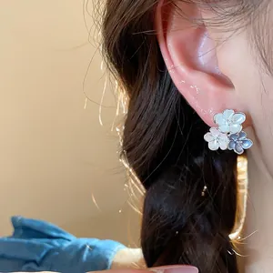 Detailed close-up of multi-colored floral enamel stud earrings worn on ear