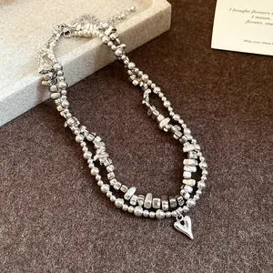 Primo piano di una collana in argento a due strati con perle irregolari e ciondolo a cuore