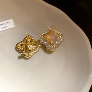 Close-up view of gold geometric earrings with champagne square stone and rhinestones