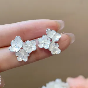 Detailed macro view of elegant white enamel flower stud earrings with a polished silver finish