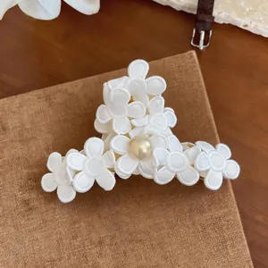 Close-up of elegant embroidered white floral hair claw clip featuring a central pearl