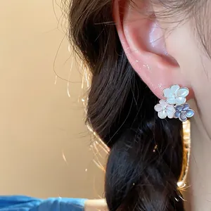 Close-up of elegant floral enamel stud earrings with delicate petals worn on ear