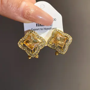 Close-up detail of luxury gold earrings featuring amber square stones and diamond pave
