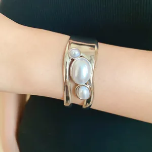 Detailed view of a vintage silver-colored cuff bracelet featuring three elegant oval pearls