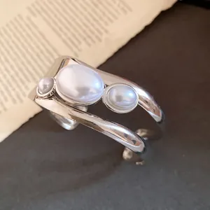 Close-up of vintage silver cuff bracelet featuring three elegant oval pearls
