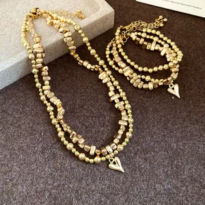Dettaglio del set collana e bracciale con perline dorate e ciondoli a cuore