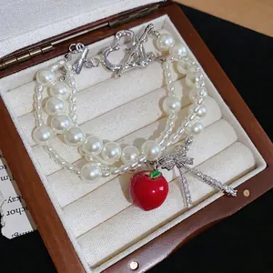 Elegant multi-layer pearl bracelet featuring a red apple pendant and zircon bow knot