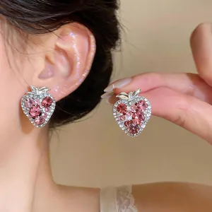 Detailed view of pink rhinestone strawberry stud earrings shown on model for size and sparkle