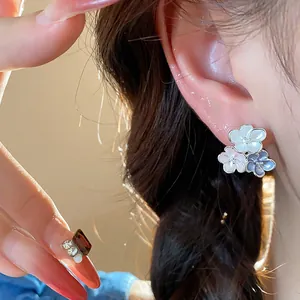 Detail close-up of elegant pearl-finish flower stud earrings with enamel drip oil design