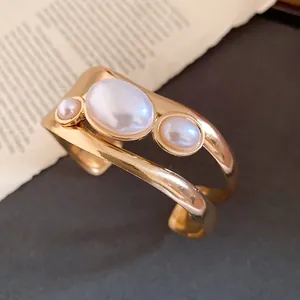 Detailed close-up view of a vintage gold-toned open cuff bracelet with oval faux pearls