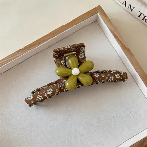 Detail of forest floral fabric claw clip with green flower and pearl center.